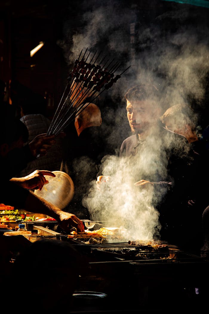 Atmospheric night market scene with chefs grilling kebabs amidst smoke.